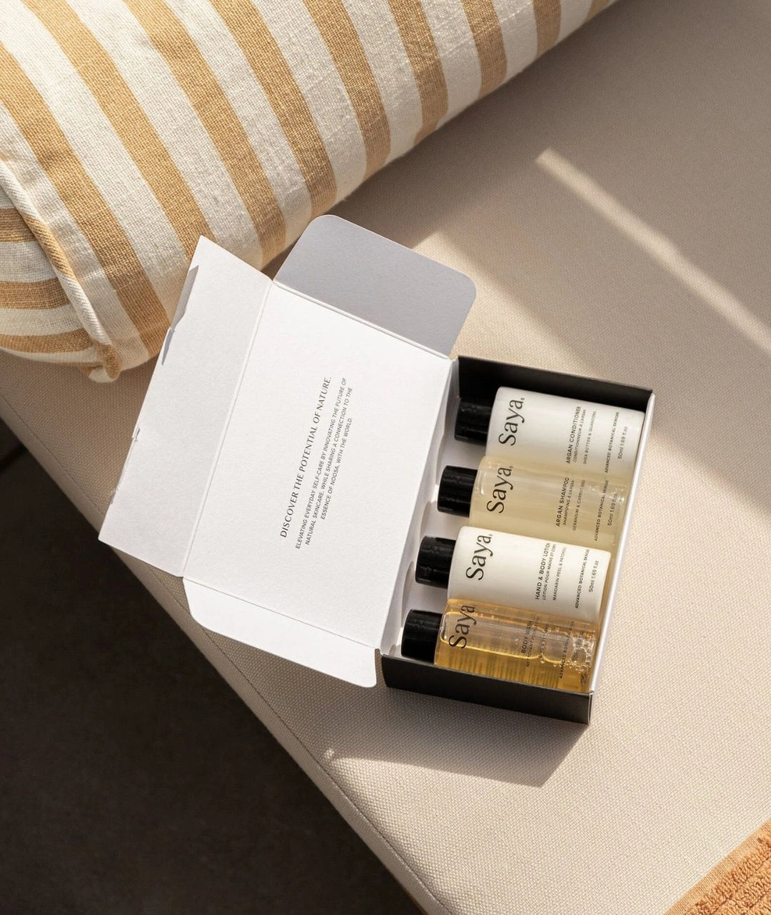 Saya Destination Essentials travel skincare kit with Argan Conditioner resting on an outdoor cushion.