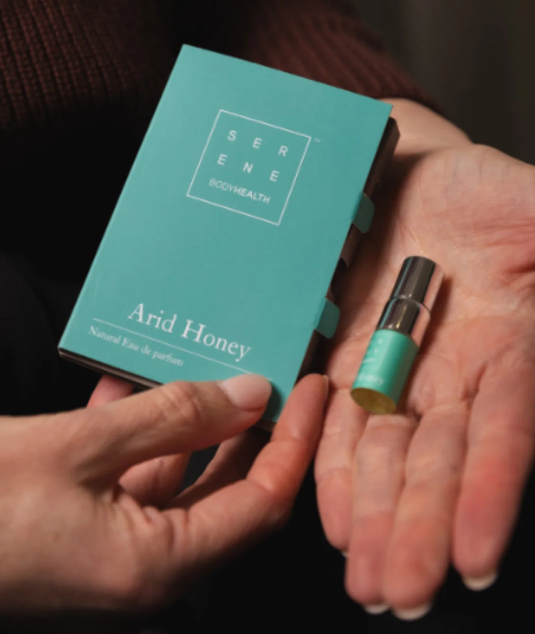 Arid Honey by Serene Bodyhealth — hands holding mini vial and teal packaging sleeve | Convenient fragrance discovery