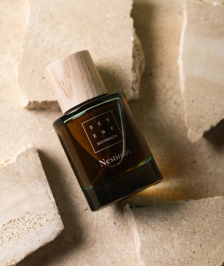 Serene Bodyhealth Nestinari Eau de Parfum bottle on natural travertine stone surface.