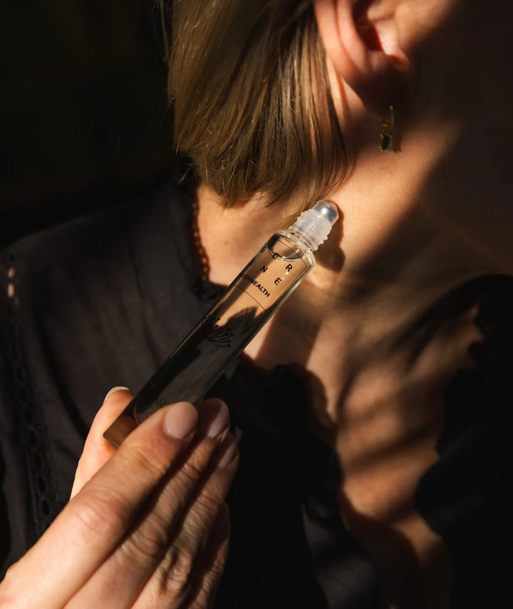 Serene Bodyhealth Essential Oil — woman applying rollerball to her neck in sunlight | Calming pulse points