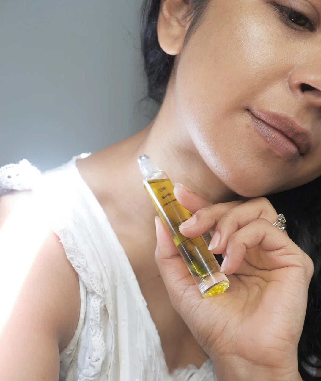 Essential Oil Rollerball by Serene Bodyhealth — woman holding bottle near her neck | Easy daily application