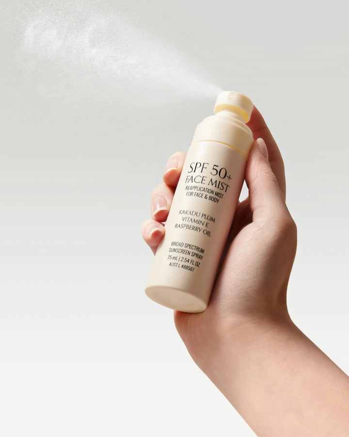Hand holding a bottle of SPF 50 face mist against a light background