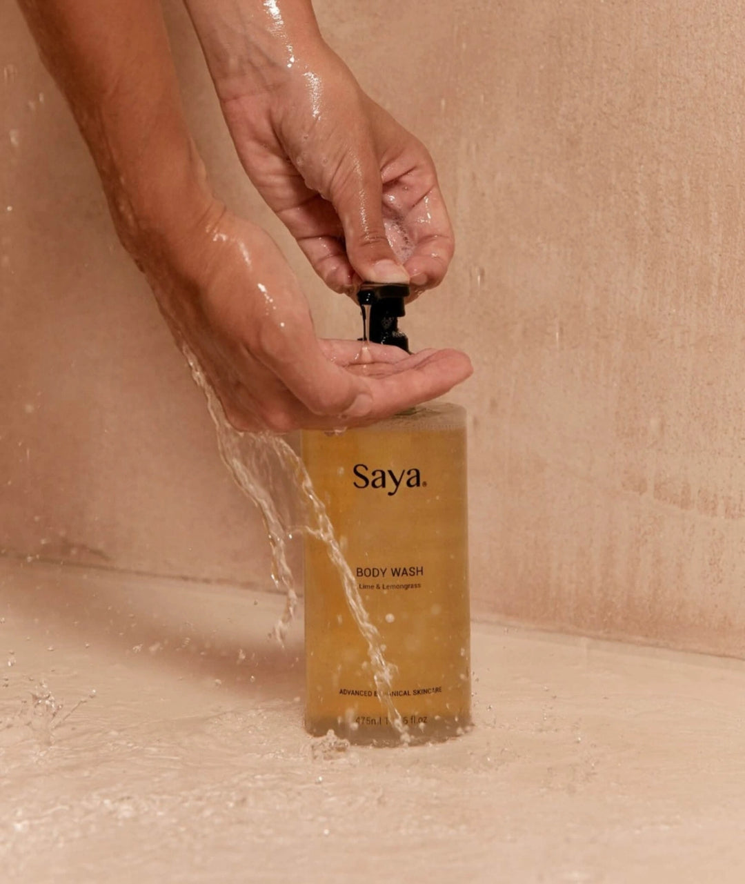 Person pumping Saya botanical Body Wash into hand under running shower water. Made in Noosa.
