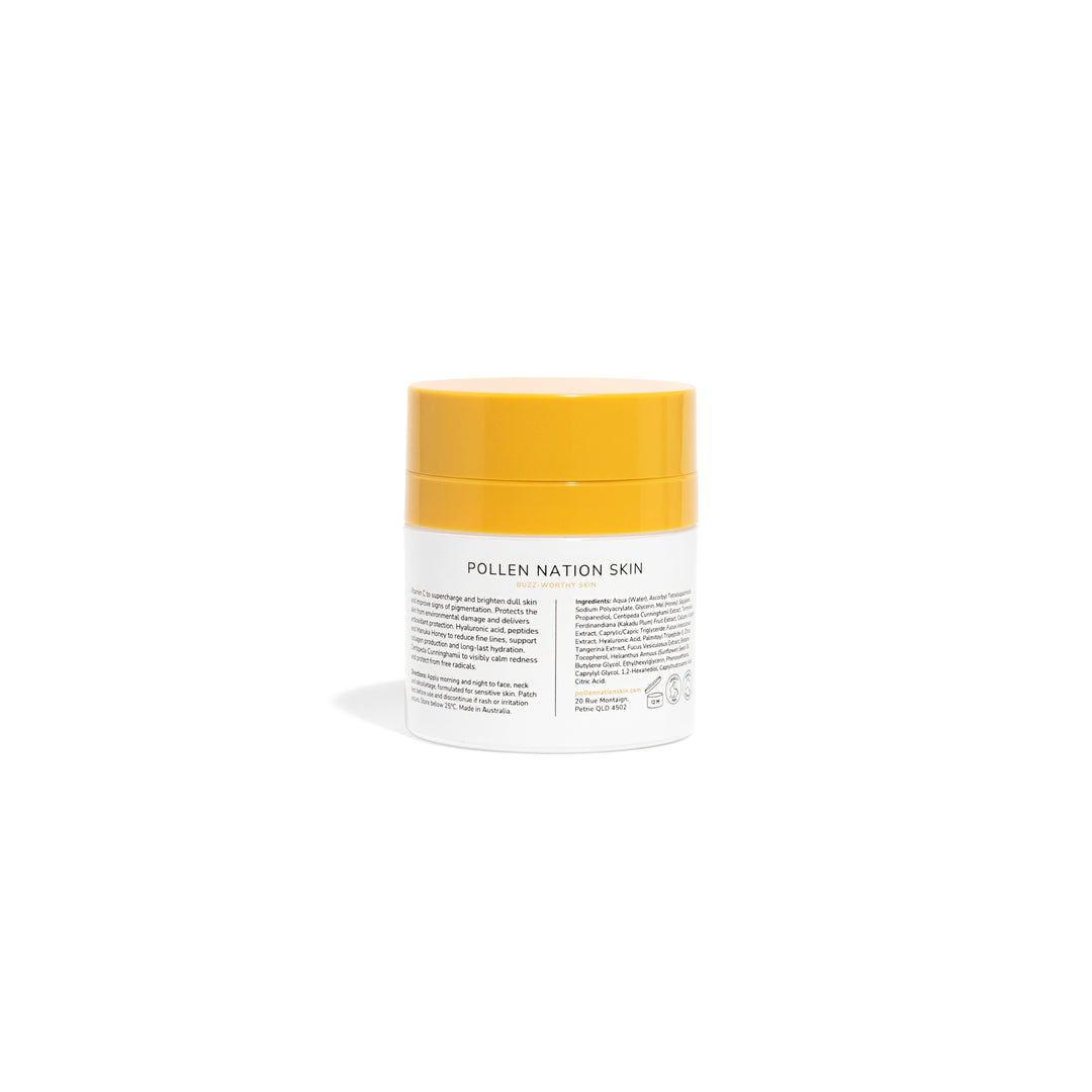A jar of Pollen Nation Skin cream with a white label and orange lid, placed on a reflective surface against a black background. The label, partially visible, lists ingredients and product information. It's designed to hydrate and brighten the skin with a 50g or 1.76 fl oz content.