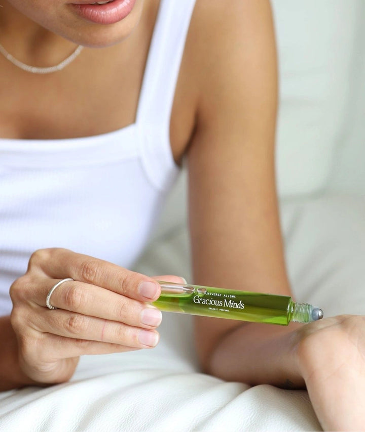 Woman applying Gracious Minds Universe Aligns organic roll-on perfume to her wrist.