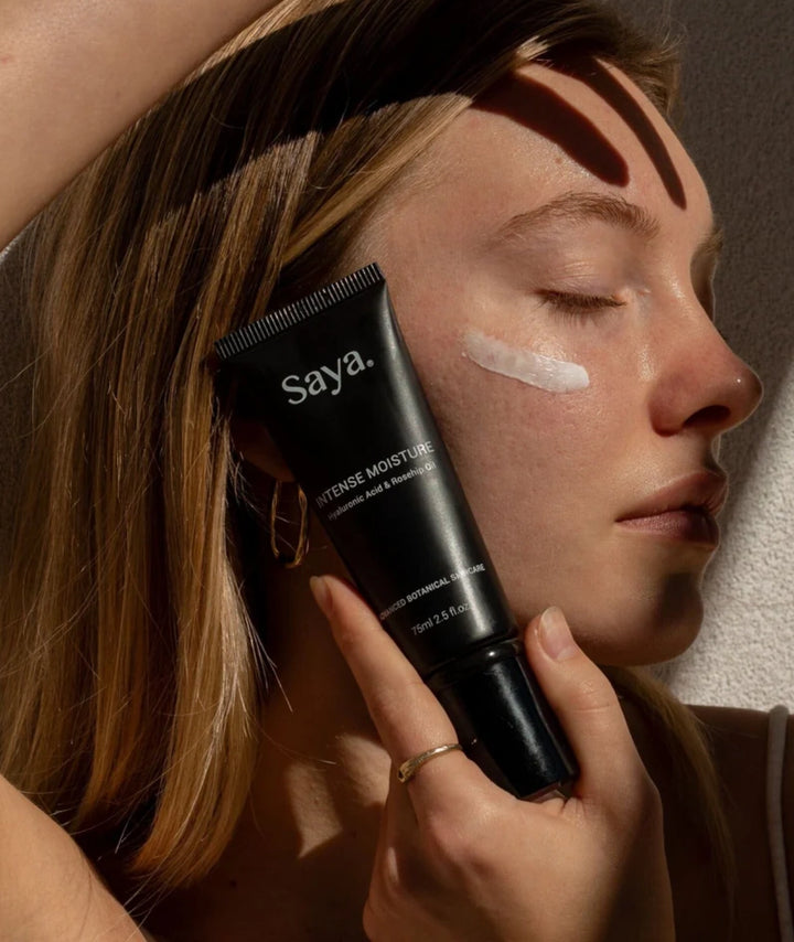 Woman applying Saya Intense Moisture cream to her cheek. Hydrating botanical skincare.