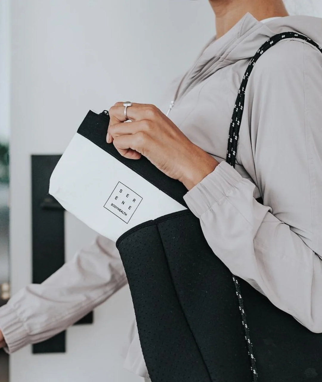 Woman carrying Serene Bodyhealth canvas travel pouch tucked into a tote bag.