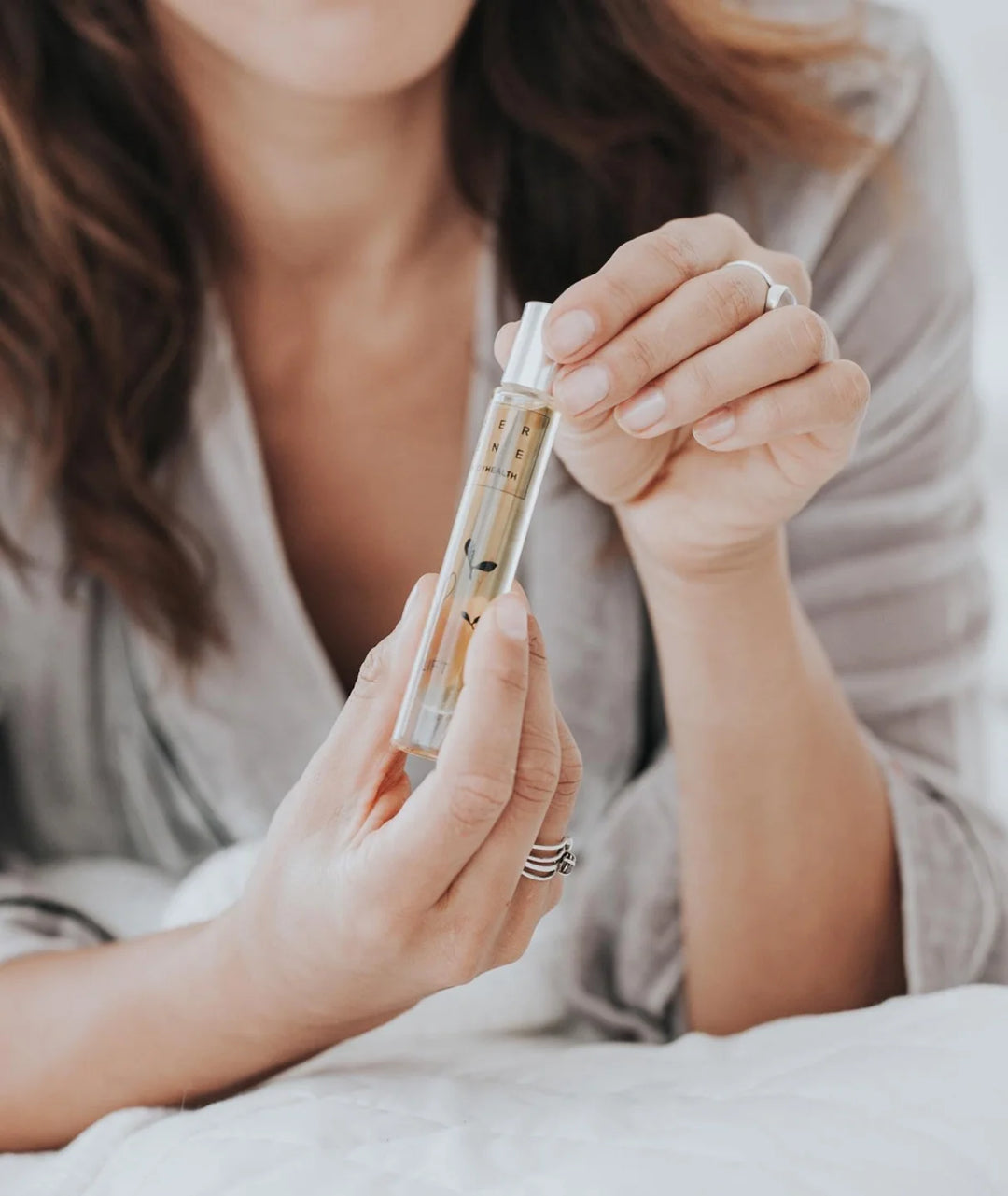 Woman holding Serene Bodyhealth Ground essential oil perfume rollerball bottle.