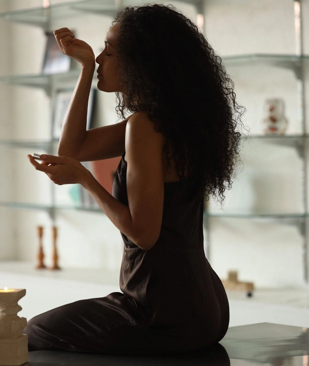 Woman smelling Gracious Minds natural perfume oil on her wrist in a lit room.